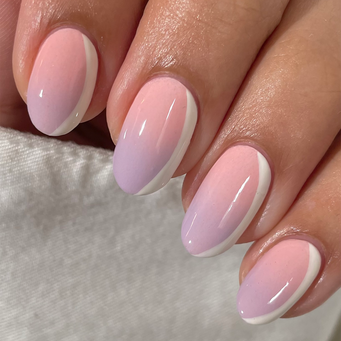 Just Peachy pastel coral pink nail polish close-up on a light skin tone with a white sweater