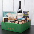 A gift basket containing a bottle of King Estate Pinot Noir, smoked sockeye salmon, summer sausage, cheddar cheese, hazelnuts covered in milk chocolate, and pepper jelly jars, all packaged in a green eco-friendly gift box.
