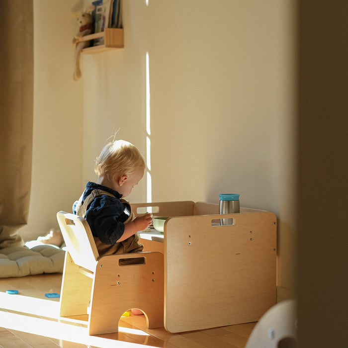 beautiful wood warm colors sunshine comming in while a toddler eats in his montessori compact table and chair set from Sapiens Child.