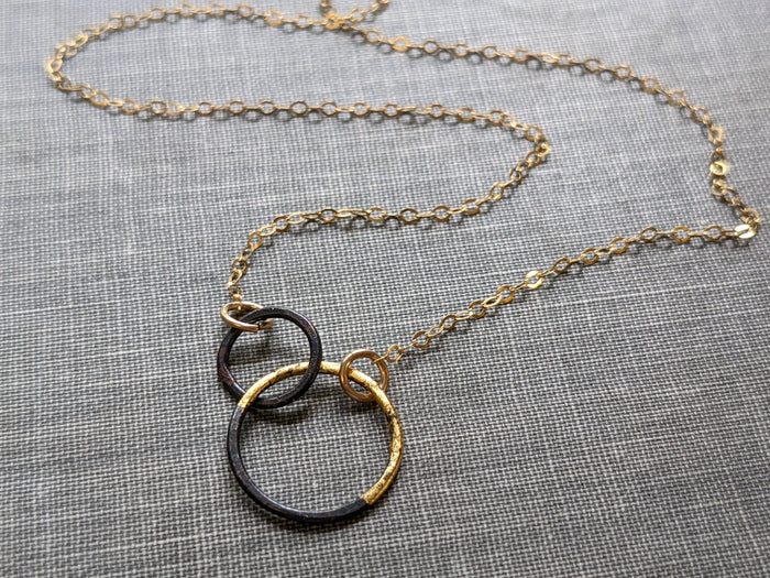 Petite Steel & Gold Interlocked Circles Necklace on a 14k gold-filled chain, showcasing its artsy interlocked design with plenty of personality.