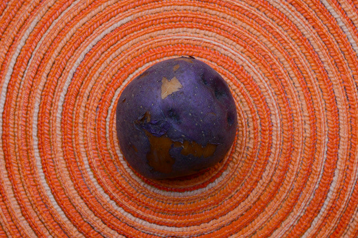 Organic Huckleberry Gold potato seed, mid-season variety, shown in round shape with smooth skin, from SeedsNow-Potatoes.