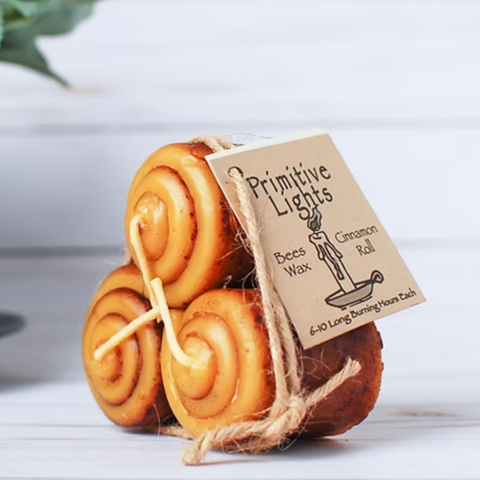 Three beeswax candles shaped like cinnamon rolls with a 'Primitive Lights' tag on a white background.